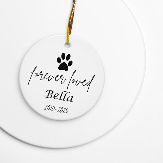 Ceramic ornament with paw print and text 'forever loved Bella 2010-2025' on a white background