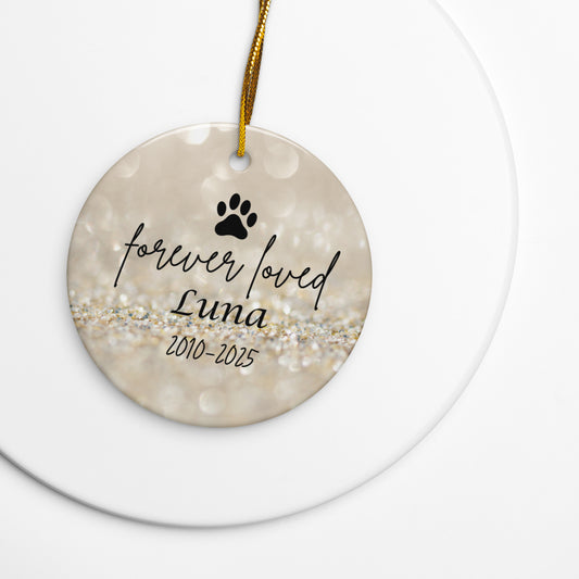 Round ceramic ornament with paw print and text 'forever loved Luna 2010-2025' on a gold background