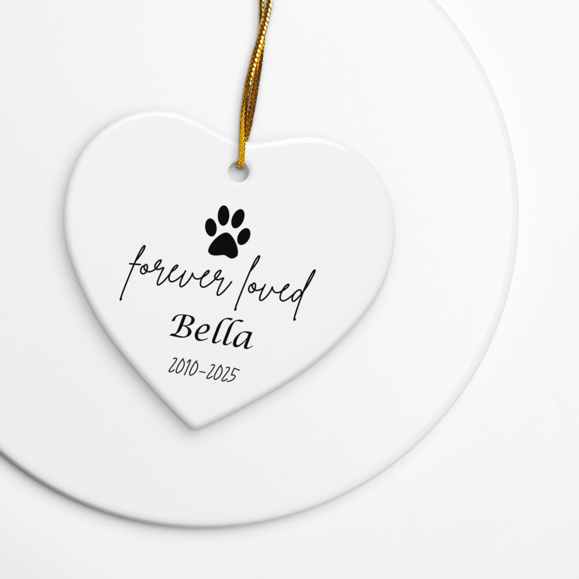 Heart-shaped ceramic ornament with 'forever loved Bella' text and paw print on a white background