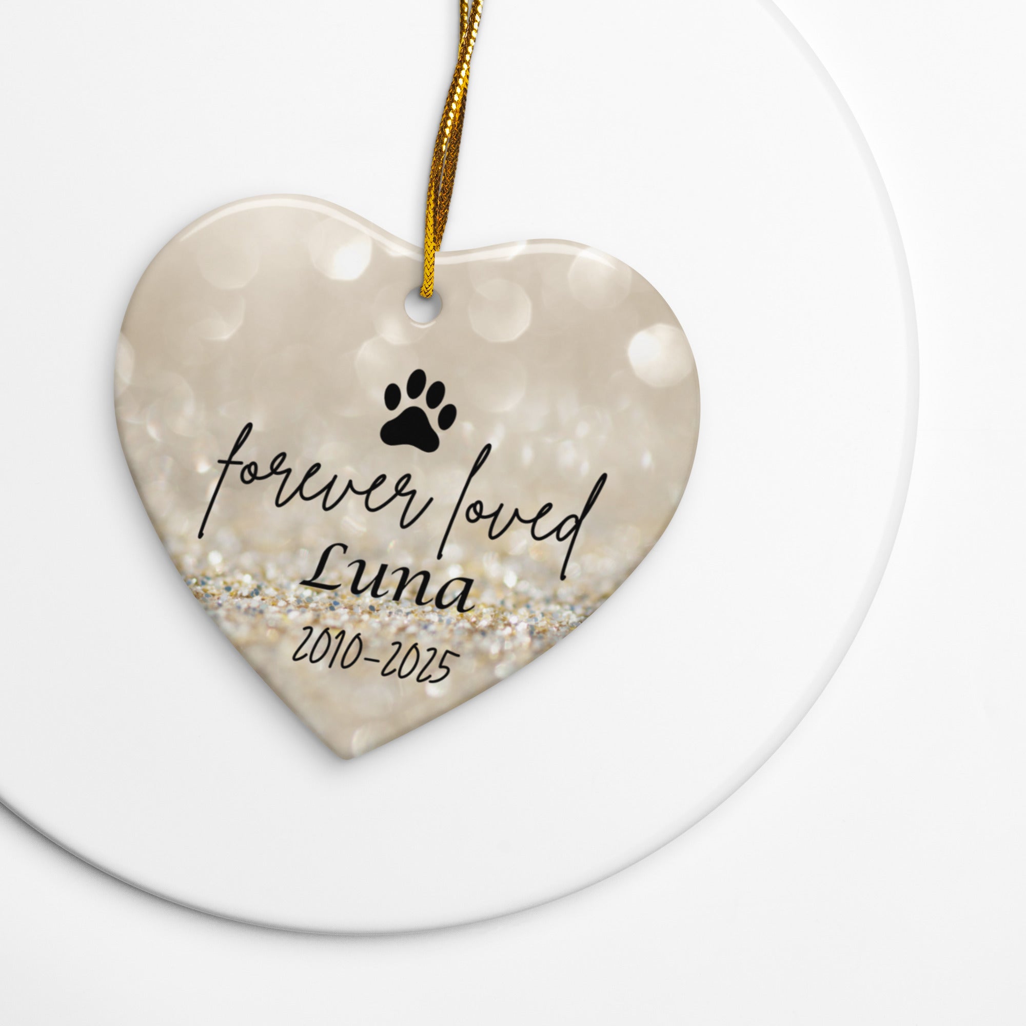 Heart-shaped ceramic ornament with 'forever loved Luna' text and paw print on a gold background