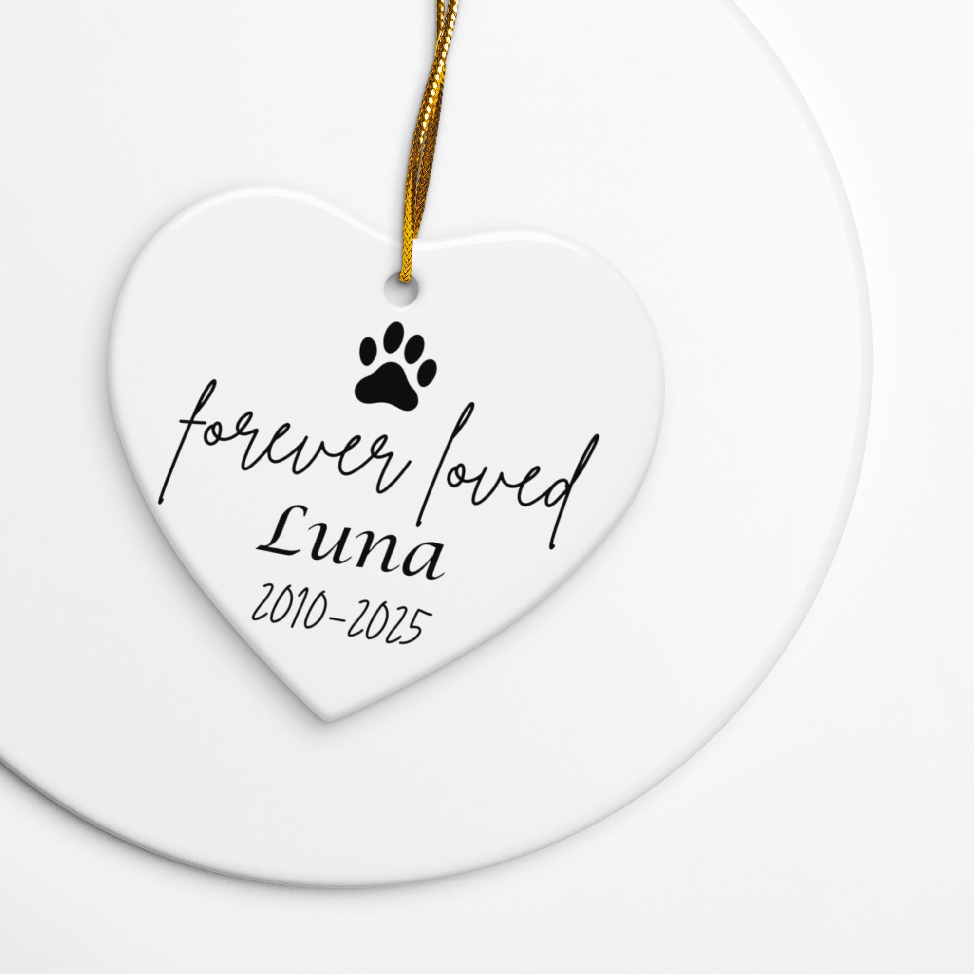 Heart-shaped ceramic ornament with 'forever loved Luna 2010-2025' text and paw print on a white background.