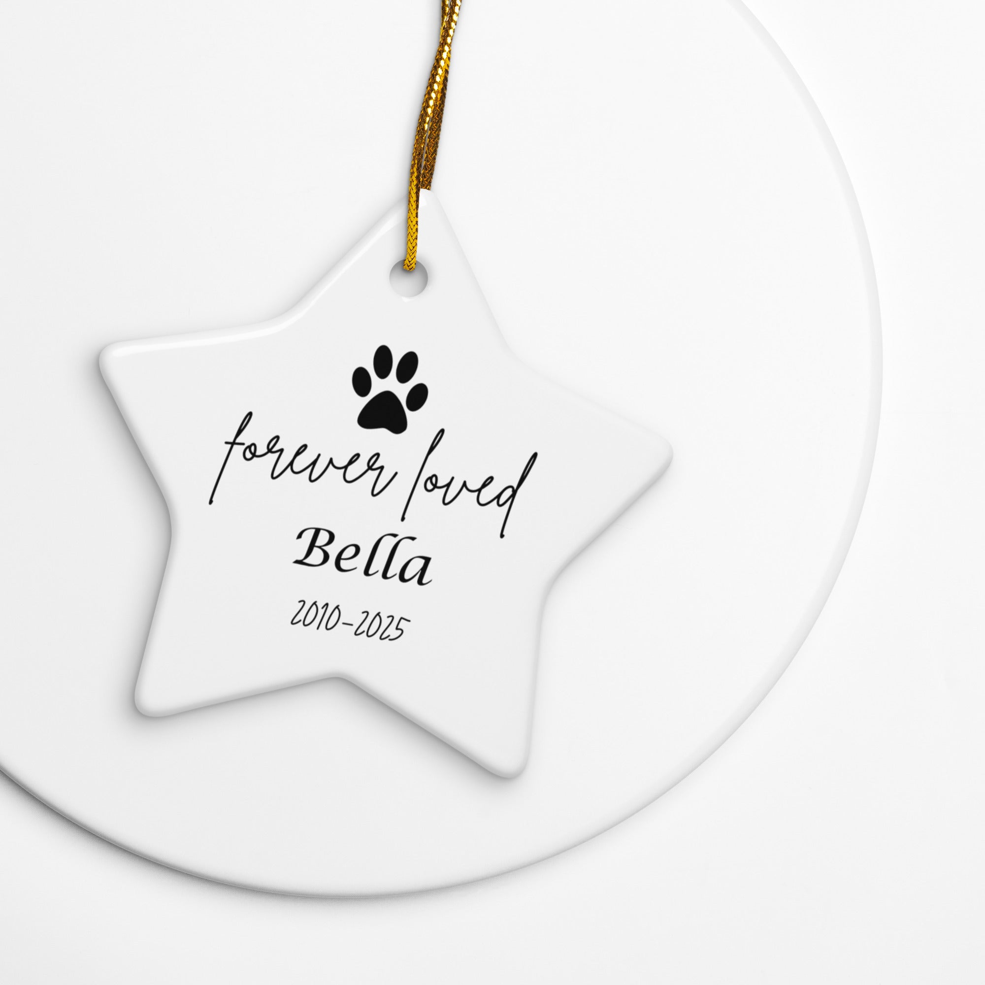 Star-shaped ceramic ornament with 'forever loved Bella' text and paw print on a white background