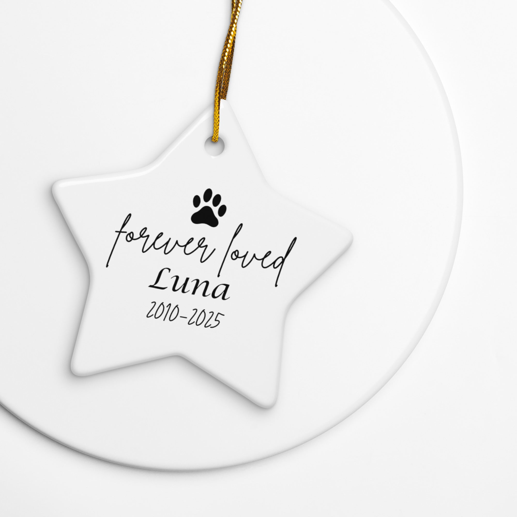 Star-shaped ceramic ornament with 'forever loved Luna 2010-2025' text and paw print on a white background.